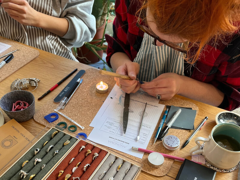 A student at a ring making class is carving a design blue wax